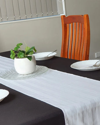 White satin striped table runner displayed on a dining table, made from a durable cotton blend to create an elegant table setting for Australian homes, restaurants, hotels and special occasions.